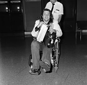 Pop singer Meat Loaf leaving Heathrow Airport in a wheelchair. 23rd June 1985
