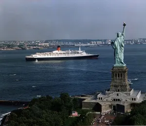 Images Dated 25th April 1992: The QE2 Ship leaves New York Harbour past the Statue of Liberty April 1992