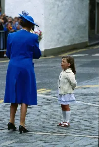 Queen Elizabeth II July 1989 taking flowers from a little girl who is looking up At her Queen Elizabeth II July 1989 taking flowers from a little girl who is looking up At her
