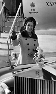 Queen Elizabeth II waves to onlookers, as she walks to her car from the aircraft