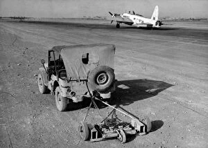 Detecting Gallery: R.A.F. engineers search an airfield for mines using a magnetic sweep attached to a jeep