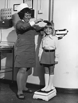 School nurse seen here measuring and weighing a pupil. 25th August 1972