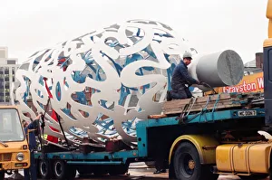 The sculpture Bottle of Notes is lifted off its low loader in the Central The sculpture Bottle of Notes is lifted off its low loader in the Central