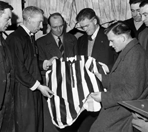 Scunthorpe United players & coaching staff examine shirt of local works team that they Scunthorpe United players & coaching staff examine shirt of local works team that they