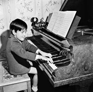 Seven year old boy playing songs on the piano which he has written himself Seven year old boy playing songs on the piano which he has written himself