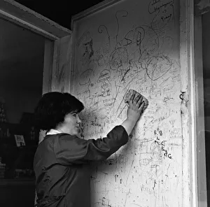 A shop assistant removes the scribbling on the wall outside her shop in Kirkby, Liverpool A shop assistant removes the scribbling on the wall outside her shop in Kirkby, Liverpool