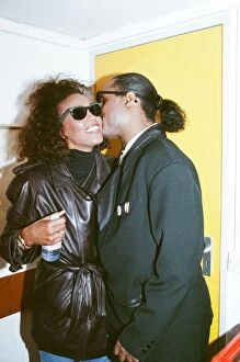 Stevie Wonder kisses Whitney Houston on the cheek as they laugh backstage at the Nelson