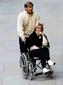 Images Dated 16th April 1992: Susan George Actress is pushed along in a wheelchair by her husband Simon MacCorkindale