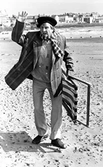 Television comedian Norman Colliercarrying a deckchair on the beach April 1991