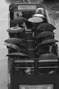 Tourists sit underneath their umbrellas on the top deck of an open top bus during a Tourists sit underneath their umbrellas on the top deck of an open top bus during a