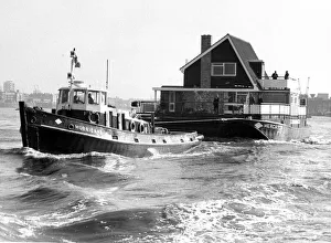 A tug boat hauling a floating home along to its new site on the River Thames September A tug boat hauling a floating home along to its new site on the River Thames September