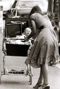 Unusual - Mother pushing a pram with her baby and a portable television set placed next Unusual - Mother pushing a pram with her baby and a portable television set placed next