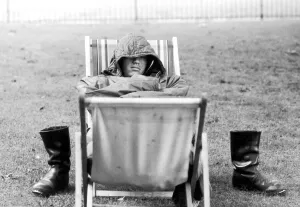Images Dated 5th August 1971: A weary traveller removes his boots as he takes a rest on a bed made from two deckchairs