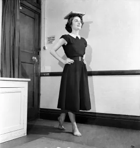 A woman balancing a book on her head during deportment classes A woman balancing a book on her head during deportment classes