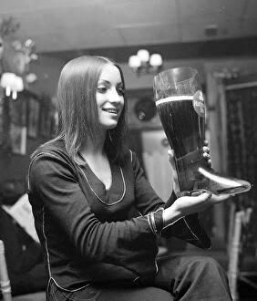 Woman drinking lager from a glass boot holding nearly 5 pints