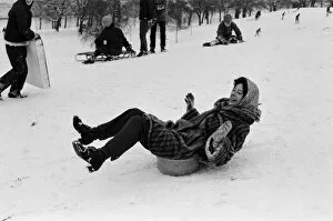 A woman sledging on a washing up bowl in Greenwich Park, London, 27th December 1970