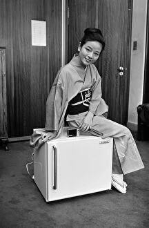 01159 Gallery: A woman wearing a Kimono sitting on a Japanese food freezer. 26th July 1965