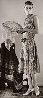 A woman wearing white and gold brocade evening gown which has a tight bodice A woman wearing white and gold brocade evening gown which has a tight bodice