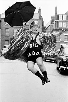 Images Dated 20th March 1980: Wrestler Shirley Crabtree alias Big Daddy jumps in the air with an umbrella