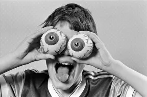 Images Dated 21st October 1986: A young boy holding fake eye ball toys up to his eyes. 21st October 1986