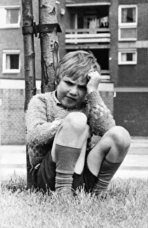A young boy sits miserable as all his friends aren t outside playing 01 / 06 / 72circa