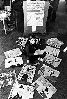 A young boy sitting on the floor among paintings and drawings which have been made by A young boy sitting on the floor among paintings and drawings which have been made by