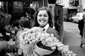A young girl of Amsterdam holding bunches of tulips during the season May 1975