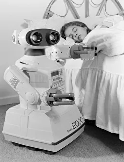 Images Dated 21st October 1986: A young girl in bed being woken by an Omnibot 2000 toy robot. 21st October 1986