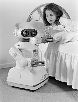 Images Dated 21st October 1986: A young girl in bed being woken by an Omnibot 2000 toy robot. 21st October 1986