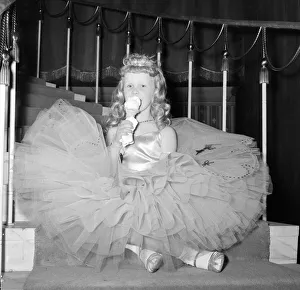 A young girl in her crinoline style ball gown takes an ice cream break during the Junior A young girl in her crinoline style ball gown takes an ice cream break during the Junior