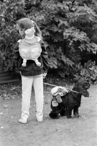 Images Dated 21st October 1986: A young girl and a dog wearing a soft toy rucksack. 21st October 1986