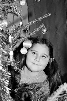 A young girl looking at decorations on a christmas tree. Teesside, December 1985