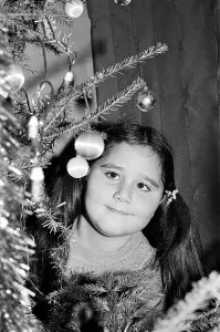 A young girl looking at decorations on a christmas tree. Teesside, December 1985 A young girl looking at decorations on a christmas tree. Teesside, December 1985