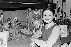 A young girl standing next to a Christmas Nativity scene. Teesside, December 1985 A young girl standing next to a Christmas Nativity scene. Teesside, December 1985