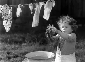 Young girl washing her clothes in a bowl of water and hanging them out to dry Young girl washing her clothes in a bowl of water and hanging them out to dry