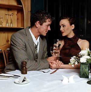 Images Dated 7th February 1996: Young man and woman holding hands at dinner table looking into each others eyes