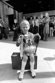 A young West Ham fan holding the FA cup trophy during the West Ham victory parade in