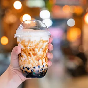 Prints of Young woman is holding, drinking brown sugar flavored tapioca pearl bubble milk tea with glass straw in night market of Taiwan, close up, bokeh Pop Art Prints: Bubble Milk Tea Print