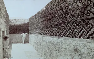 Ruins of the archaeological site of Mitla in Mexico. The eastern hall of one of the palaces with the walls covered with carved friezes of geometric patterns. Two Mexicans inside the room