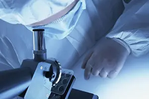 Chemist In Lab Coat Prints: Chemist looking through a microscope