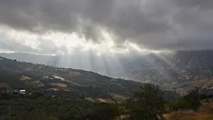 Greek Island Landscapes Prints: Dramatic landscape with sun rays breaking through a cloud cover