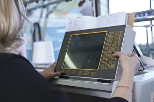 Automated Manufacturing Process Prints: Female operator setting programme at knitting machine control panel view