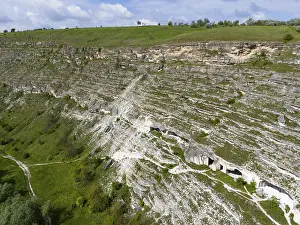Prints of Limestone cliffs with caves and grass on a steep wall under blue sky, aerial view, cave dwellings, FLALT-orhei, Orheiul Vechi, archaeological site, protected landscape area, Orhei district Moldova Prints: Limestone Cliffs Print, Orheiul Vechi, Moldova