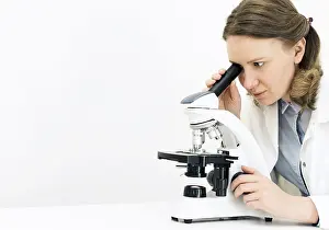 Female Scientist Prints: Scientist using microscope in laboratory