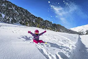 Prints of Smiling girl sitting on snow and throwing snow powder up to the air, mountains and forest in a background. Winter ski holidays, Andorra, Pyrenees Andorra Prints: Smiling Girl Throwing Snow in Andorra Winter Print