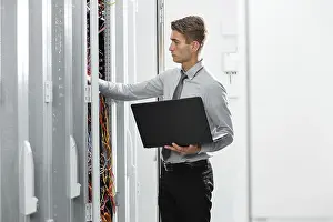 Female IT Professional Prints: Technicians using laptop while analyzing server in server room