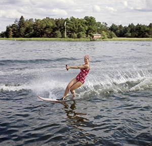Retro Swimwear Fashion Prints: Waterskiing in the 1960s. A young woman in a patterned bathing suit passes the photographer on her waterskis