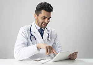 Stethoscope Use Prints: Young smiling internist using tablet computer